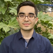 Man wearing glasses and smiling for a photo with plants in the background
