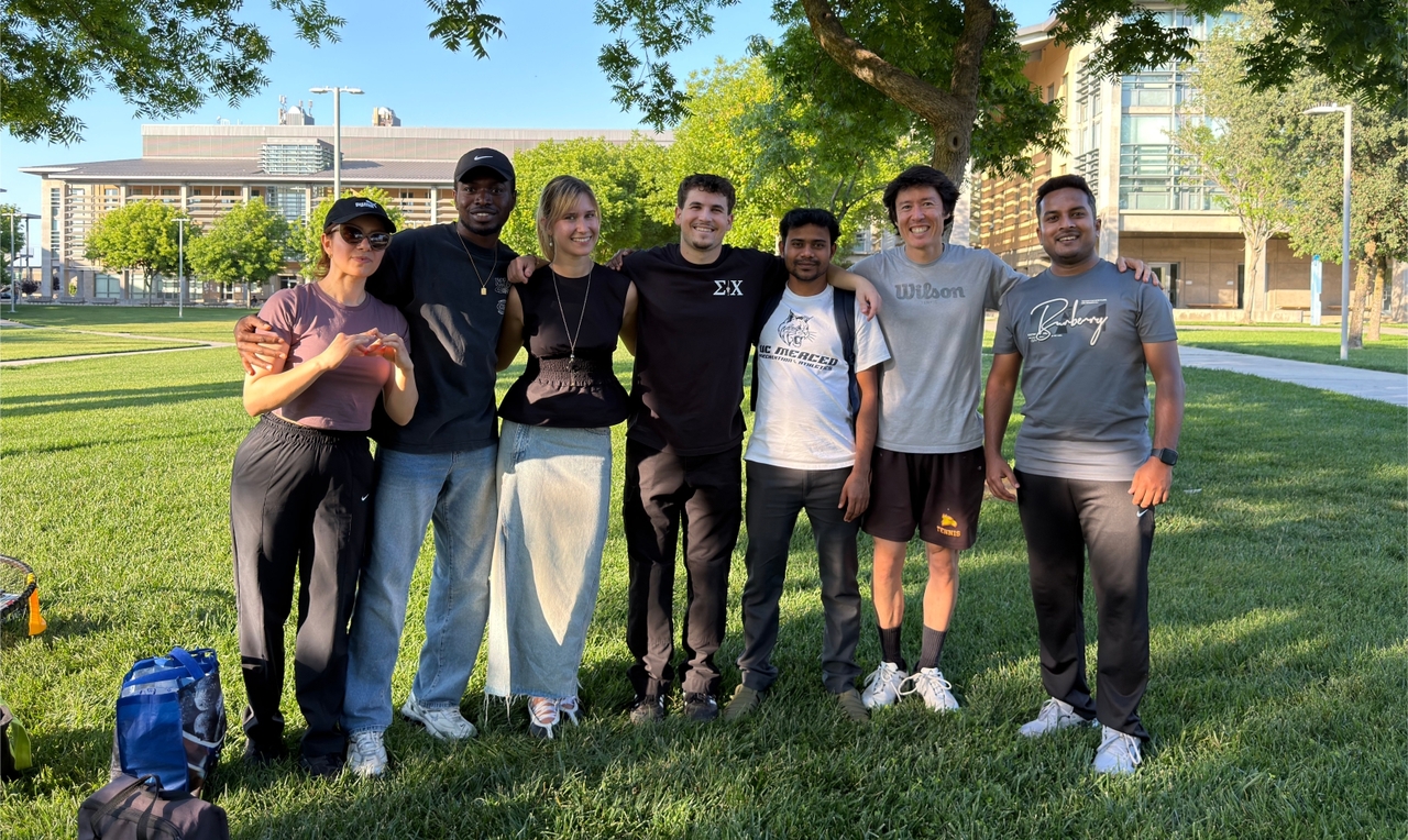 Seven people pose for a photo in a park.