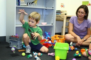 A research assistant playing with toys with a toddler in the waiting area of the lab.